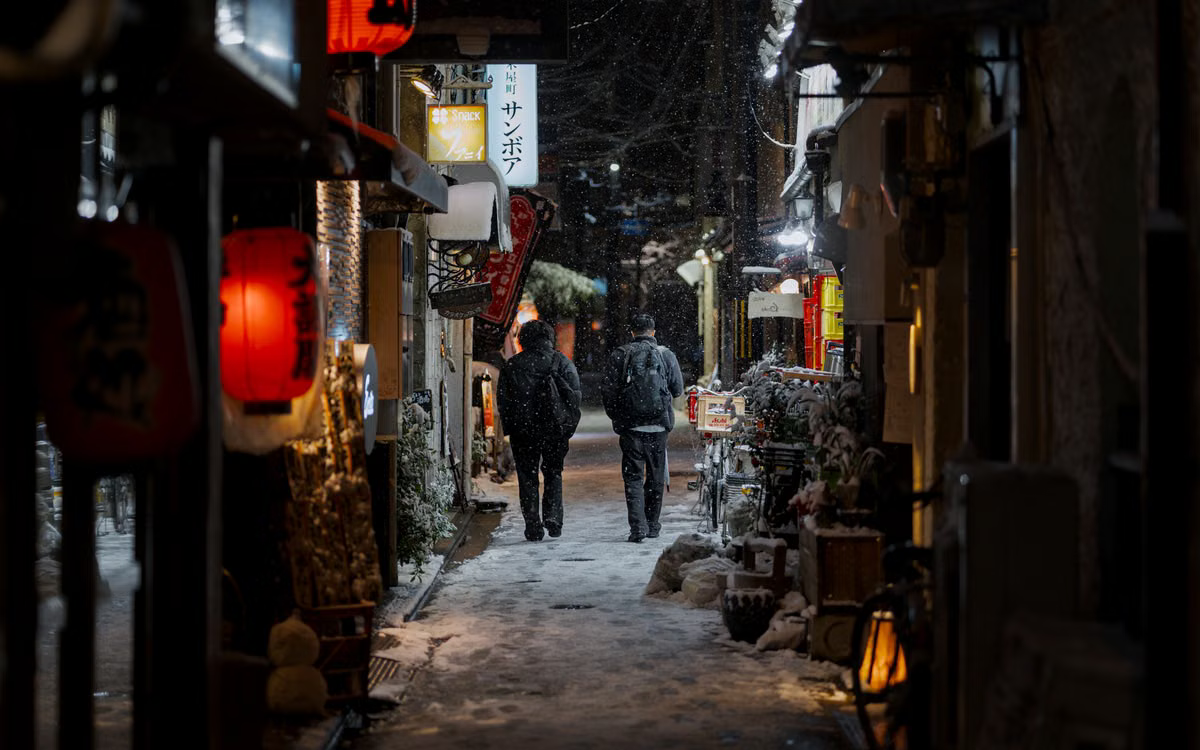 Night street photography of a snowy Japanese alley lit by lanterns